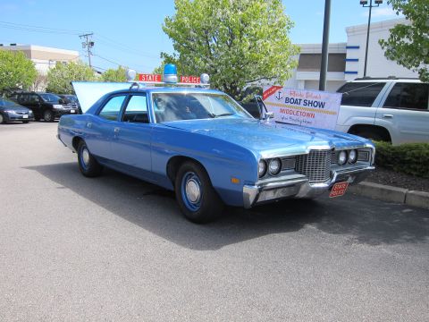 1991 Ford LTD Crown Victoria - blue early-1970s Ford four-door State Police sedan with roof light displayed at a Rhode Island Boat Show, hood open.
