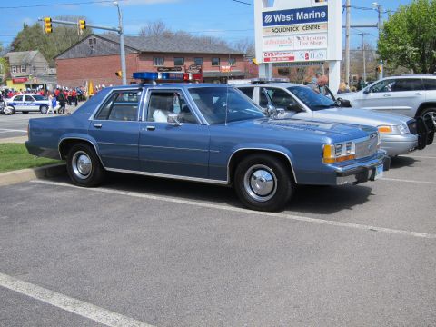 1991 Ford LTD Crown Victoria - Front three-quarter view of a blue Ford LTD Crown Victoria police sedan with light bar parked outside a West Marine store.
