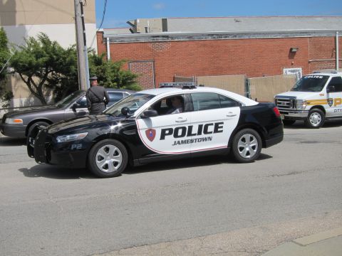 1991 Ford LTD Crown Victoria - black-and-white Jamestown Police Ford Taurus Interceptor sedan, unit P2, on a street with an officer and another cruiser nearby.