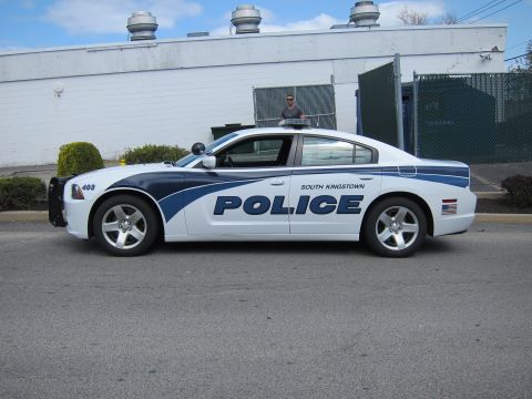 1991 Ford LTD Crown Victoria - white and blue Dodge Charger South Kingstown Police sedan, unit 403, parked in profile with a man standing behind it.