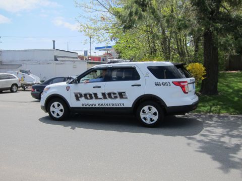 1991 Ford LTD Crown Victoria - white Ford Explorer SUV marked Police, Brown University, shown rear-three-quarter on a street lined with trees.