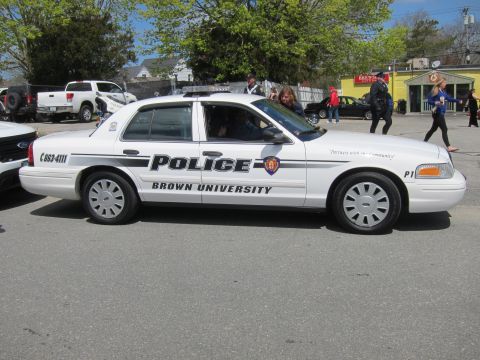 1991 Ford LTD Crown Victoria - white Ford Crown Victoria marked Police, Brown University, unit P1, parked in profile with people walking nearby.