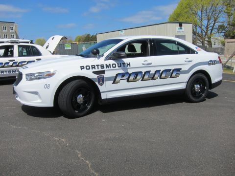 1991 Ford LTD Crown Victoria - white Ford Taurus marked Portsmouth Police, unit 08, with black steel wheels, shown front-three-quarter on a paved lot.