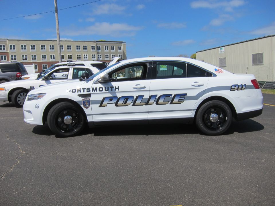 White Ford Taurus Portsmouth Police sedan with black wheels, side profile
