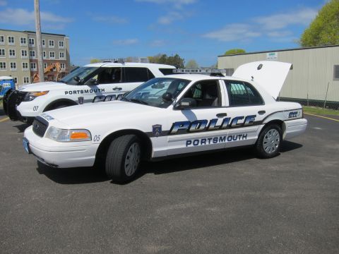 1991 Ford LTD Crown Victoria - white Ford Crown Victoria Portsmouth Police sedan unit 05 sits with its hood up in a sunny paved lot beside another cruiser.
