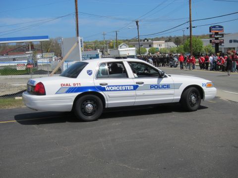 1991 Ford LTD Crown Victoria - white Worcester Police Ford Crown Victoria sedan with blue striping is parked in a lot with a crowd gathered in the background.