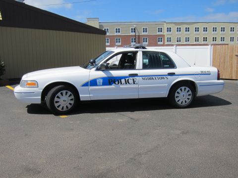 1991 Ford LTD Crown Victoria - white Ford Crown Victoria Middletown Police sedan with blue striping shown in side profile beside a building.