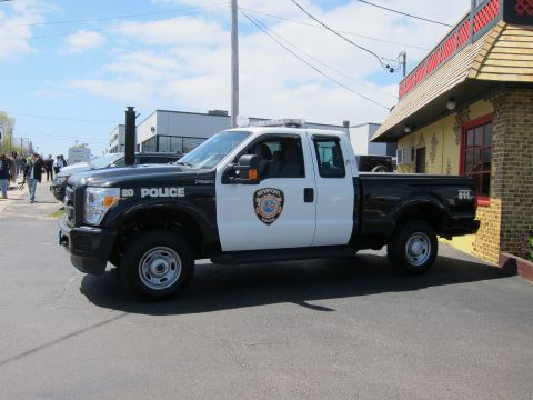 1991 Ford LTD Crown Victoria - black-and-white Ford F-250 Super Duty Newport Police pickup truck parked along a street near a yellow building.