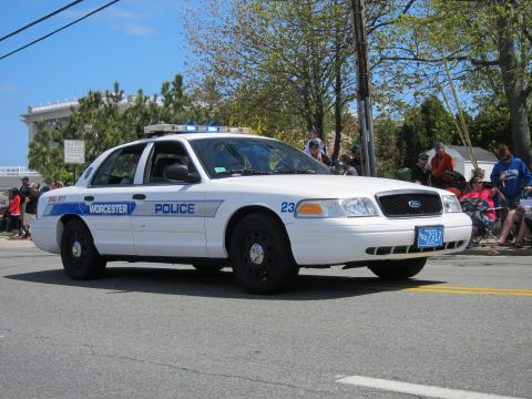 1991 Ford LTD Crown Victoria - white Ford Crown Victoria Worcester Police cruiser unit 23 with light bar drives a parade route past seated spectators.