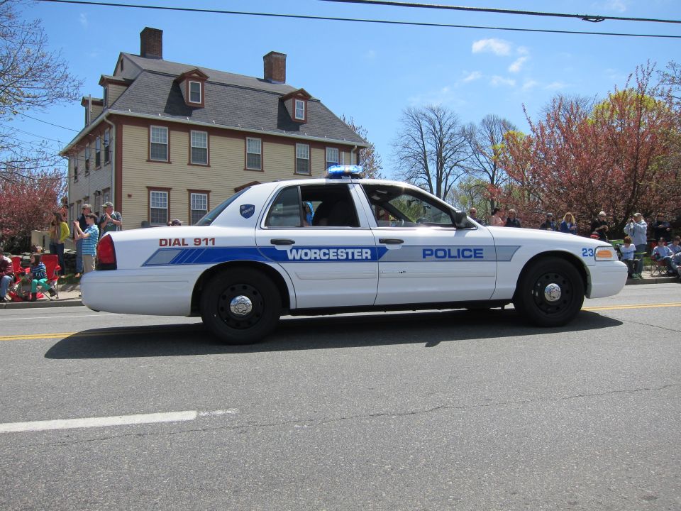 White Ford Crown Victoria Worcester Police cruiser, side view, past tan house