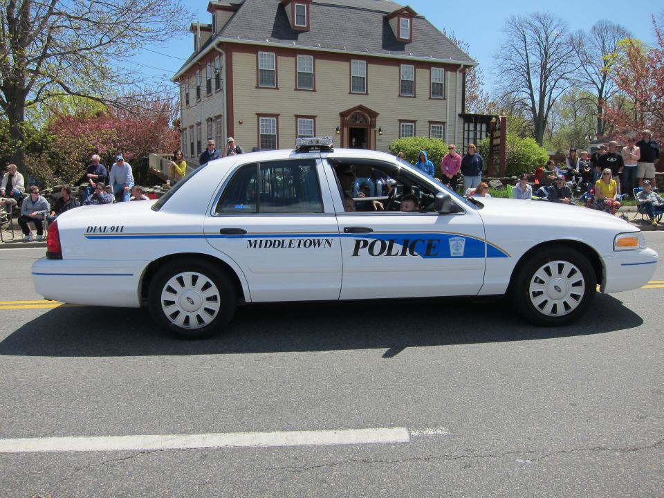 White Middletown Police Crown Victoria parked in front of a gray colonial house