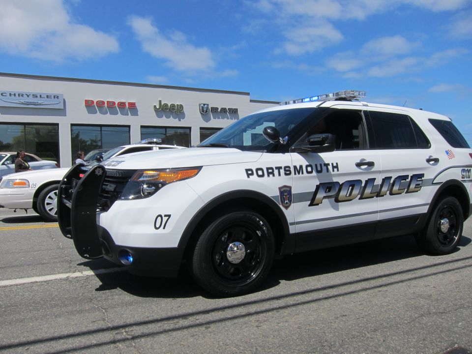 White Portsmouth Police SUV number 07 parked in front of a dealership