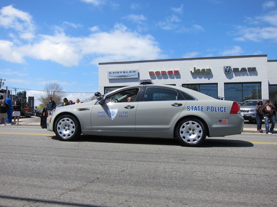 Silver State Police sedan with light bar passing a dealership