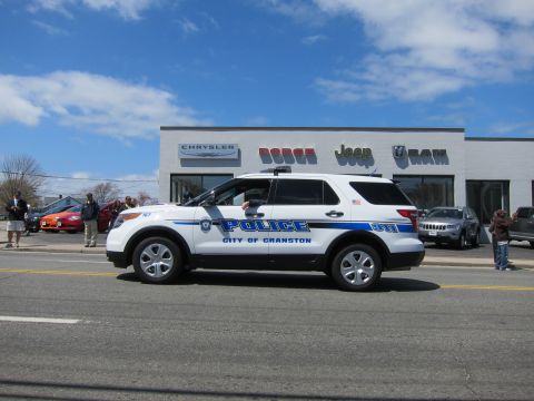 1991 Ford LTD Crown Victoria - white Ford Explorer marked Police City of Cranston drives past a Chrysler Dodge Jeep Ram dealership.