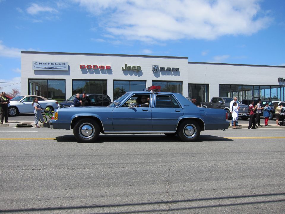 Blue Ford LTD Crown Victoria with roof light in front of a dealership