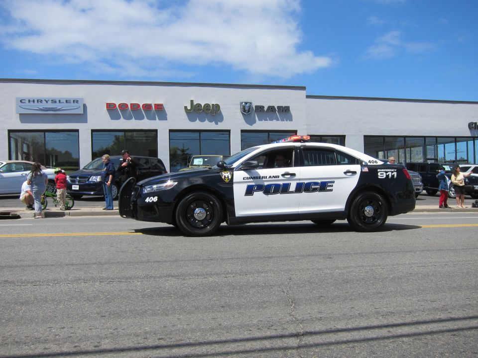 Black and white Cumberland Police sedan number 406 in front of a dealership