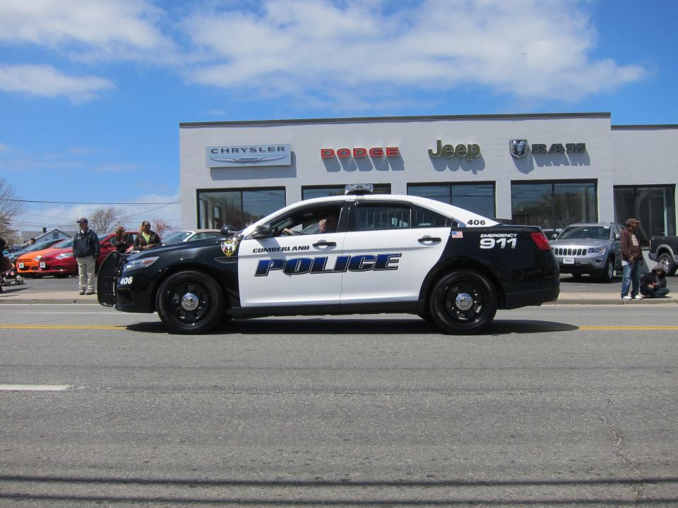 Black and white Cumberland Police Taurus 406 passing a Jeep Ram dealership