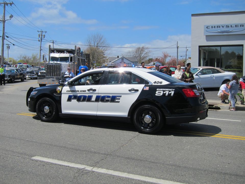 Black and white Cumberland Police Taurus 406 on a street with a tow truck behind