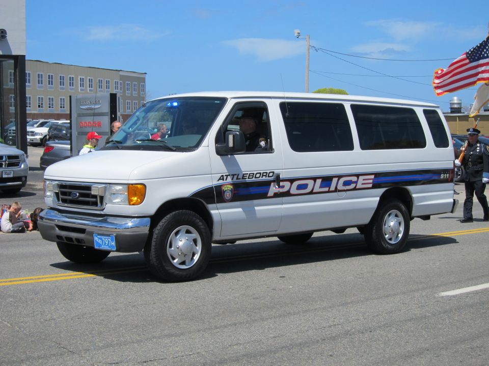 White Ford E-Series passenger van marked Attleboro Police in a street parade