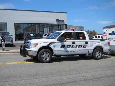 1991 Ford LTD Crown Victoria - white Charlestown Police Ford crew-cab pickup with front brush guard and roof lights drives along a parade route.