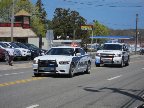 1991 Ford LTD Crown Victoria - white Dodge Charger and a white Chevrolet Tahoe, both marked Police with blue lights, drive side by side past a pizzeria.