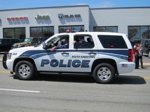 1991 Ford LTD Crown Victoria - white South Kingstown Police Chevrolet Tahoe SUV, number 463, drives past a Dodge-Jeep-RAM dealership.