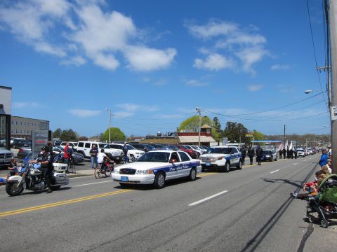 1991 Ford LTD Crown Victoria - wide street scene shows Pawtucket Police cruisers and a police motorcycle parading under a bright blue sky.