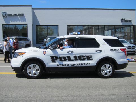 1991 Ford LTD Crown Victoria - white Brown University Police Ford Explorer SUV, unit P4, drives past a RAM dealership during a parade.