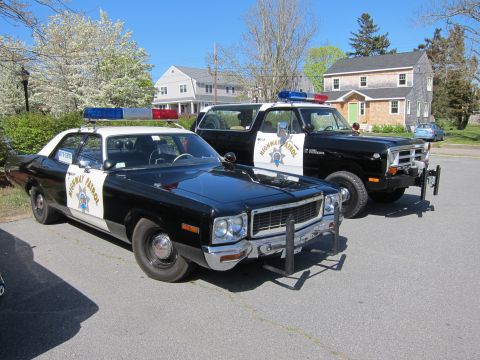 1991 Ford LTD Crown Victoria - restored black and white California Highway Patrol Dodge sedan parked beside a matching Ramcharger 4x4 with front push bars.