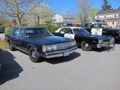 1991 Ford LTD Crown Victoria - dark blue Ford LTD Crown Victoria sedan sits parked next to a row of vintage black and white police cars.