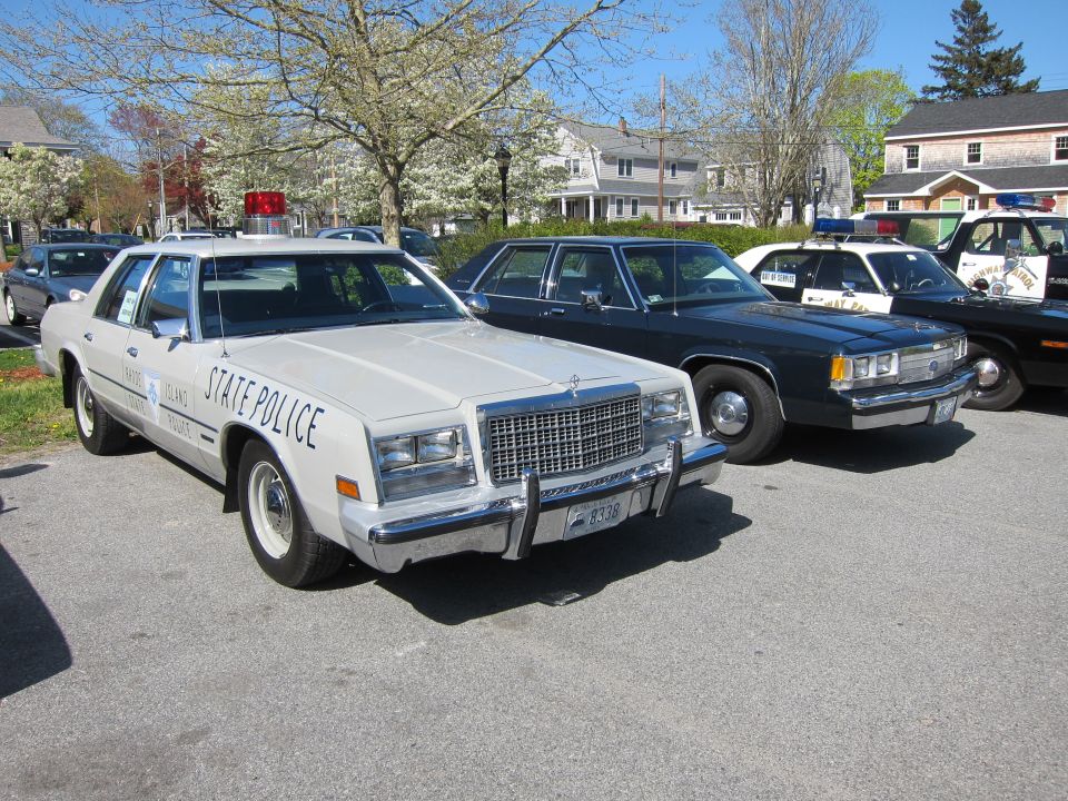 White vintage State Police sedan parked in a row of classic police cars on a lot