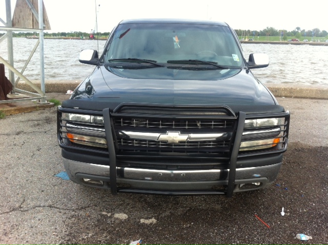 Black 2001 Chevrolet Silverado 1500 with a chrome grille and a black bull bar, parked by the water