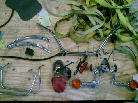 1995 Ford F-150 - Various motorcycle parts, including handlebars, a taillight, and turn signals, are arranged on a wooden surface.