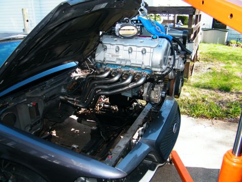 2004 Ford Crown Victoria - A new engine is being installed into a car using an engine hoist and crane.