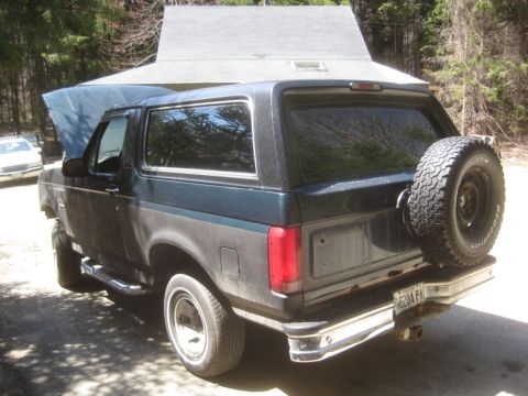 1993 Ford Bronco - Rear view of a Ford Bronco SUV with its hood open and a spare tire mounted externally.