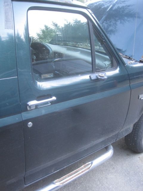 1993 Ford Bronco - The side view of a green 1993 Ford Bronco shows its door, handle, and running board, with the hood ajar.