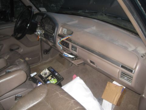 1993 Ford Bronco - The interior of a 1993 Ford Bronco shows a brown dashboard and seats with some items on the floor.