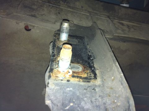1992 Ford F-150 - This image shows a close-up view of a rusted metal bracket with bolts, likely from the undercarriage of a vehicle.