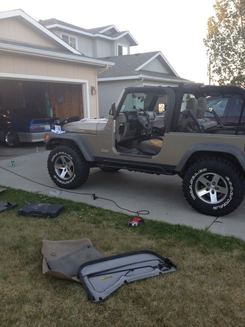 2005 Jeep Wrangler - Jeep Wrangler parked outside a garage with its doors and soft top components removed and placed on the lawn.