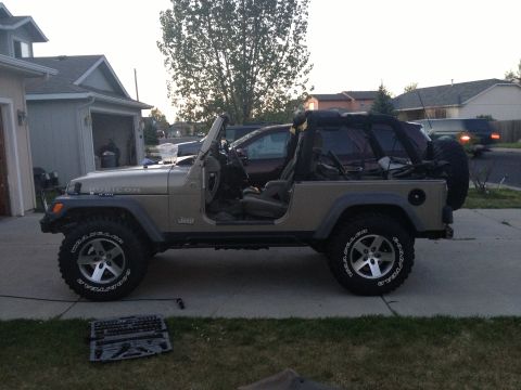 2005 Jeep Wrangler - This tan Jeep Wrangler, identified as a Rubicon, is shown from the side with its doors removed, suggesting a 2005 model year.