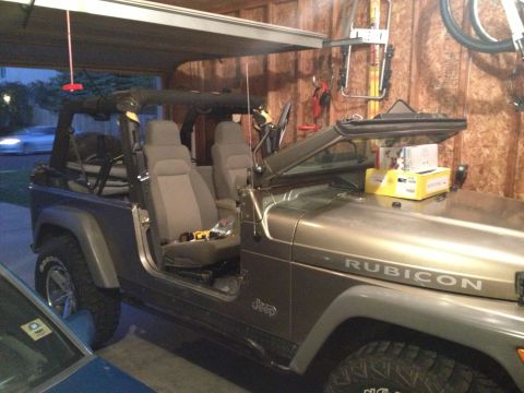 2005 Jeep Wrangler - A Jeep Wrangler is parked inside a garage with its doors removed, revealing the interior seats.