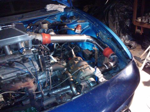 1995 Ford Probe - The engine bay of a blue car shows modifications including a turbocharger and intercooler piping.