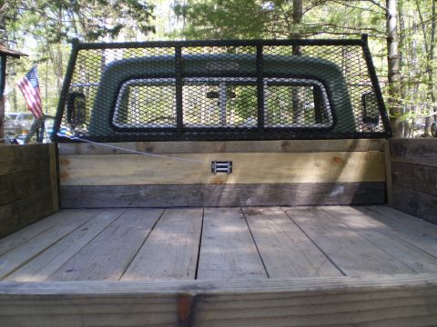 1979 Ford Bronco - The rear of a truck bed shows wooden planks and a metal cage, with an American flag in the background.