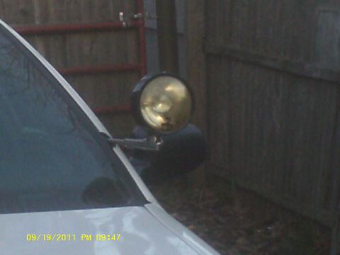 2006 Ford Crown Victoria - Spotlight mounted on the side of a vehicle, with a fence in the background.