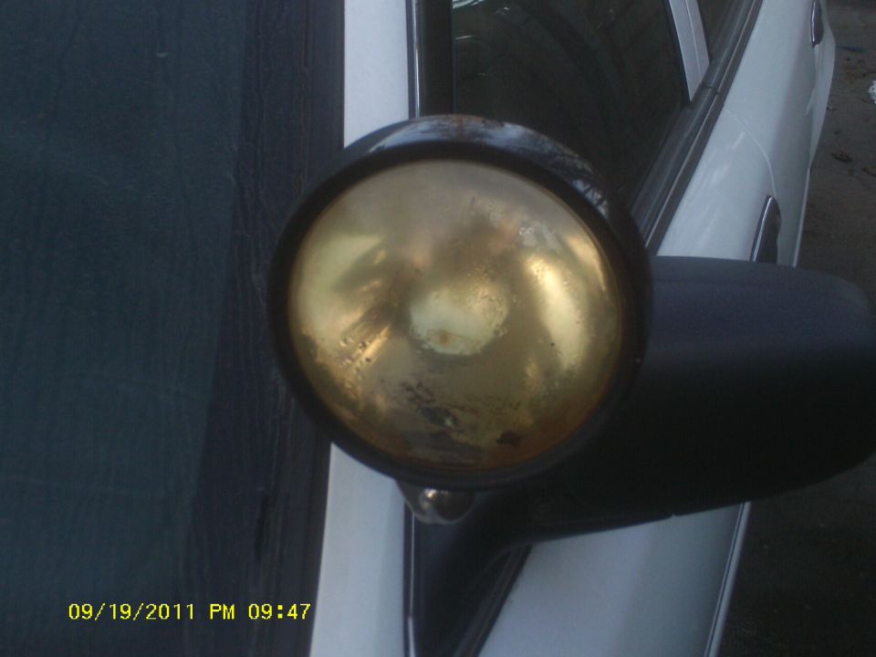 Close-up of a gold spotlight mounted on the side of a white car