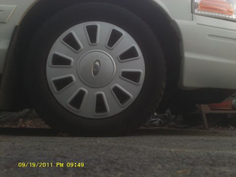 2006 Ford Crown Victoria - Close-up of the wheel and fender of a 2006 Ford Crown Victoria, showing the distinctive hubcap design.