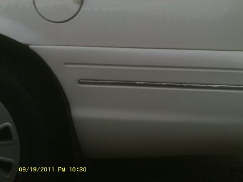 2006 Ford Crown Victoria - Close-up of a white vehicle's side panel, showing trim detail and a portion of the tire.