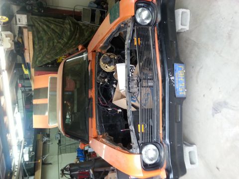 1973 Chevrolet Nova - The vehicle is undergoing some work in a garage, with its hood open and engine components visible.