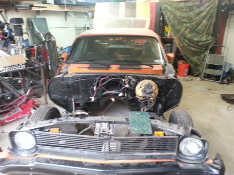 1973 Chevrolet Nova - The front of an orange 1973 Chevrolet Nova is visible, with its engine bay disassembled in a garage setting.