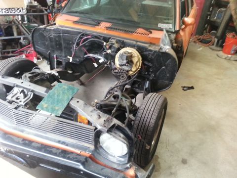 1973 Chevrolet Nova - Front end of an orange 1973 Chevrolet Nova is disassembled, showing the engine bay and suspension components.